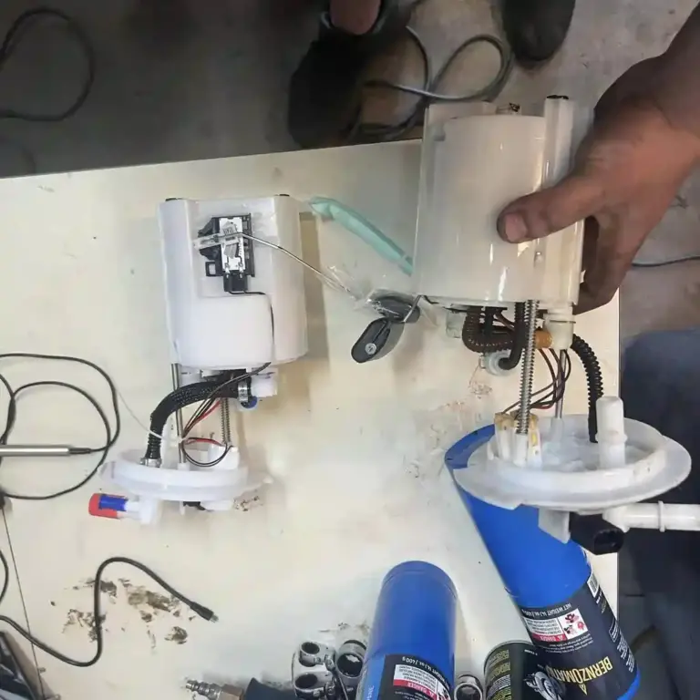 Mechanic with two fuel pumps on a table, performing a fuel pump replacement at T Autocare Takedown in Broken Arrow